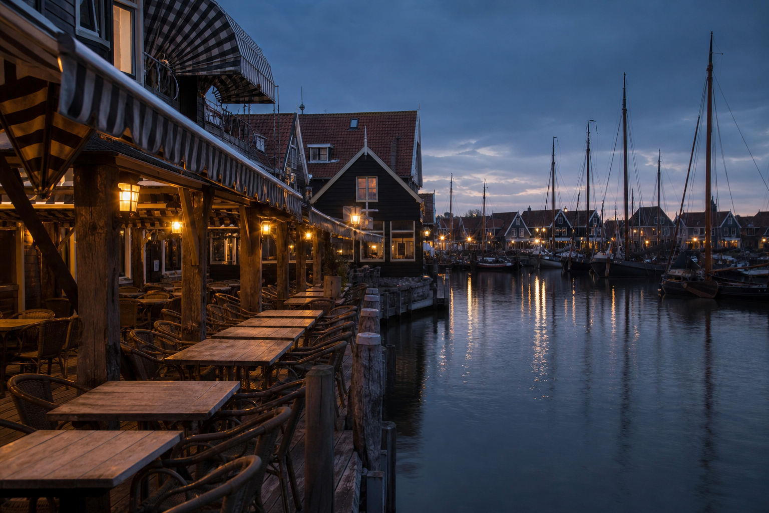 Restaurantterrassen an einem Hafenkai in einer niederlaendischen Stadt in der Abenddaemmerung